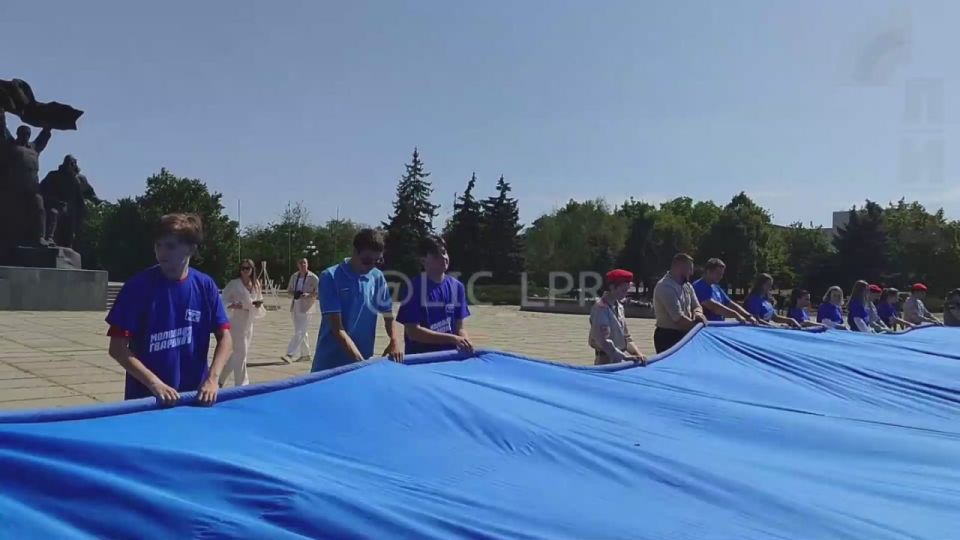 Более 150 молодежных активистов развернули 60-метровый триколор в преддверии Дня Государственного флага России у памятника Воинам-освободителям в Луганске